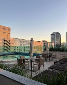 a rooftop patio with tables and umbrellas and a pool at Studio Alto Padrão Centro do Rio in Rio de Janeiro