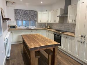 eine Küche mit weißen Schränken und einem Holztisch in der Unterkunft Town centre Victorian period 3 bedroom home in Bishops Castle