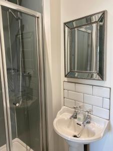 ein Badezimmer mit Waschbecken, Dusche und Spiegel in der Unterkunft Town centre Victorian period 3 bedroom home in Bishops Castle