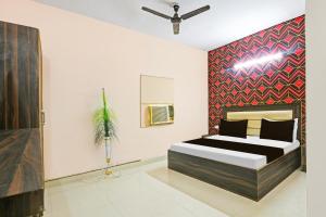 a bedroom with a bed and a red wall at Hotel O Gulabi Delight in Faridabad