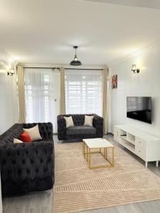 a living room with a black couch and a tv at Marleydalastays in Kisumu