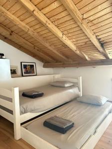 two white bunk beds in a room with wooden ceilings at Quinta Maria Gil - A in Lourinhã