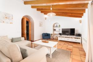Una sala de estar con un sofá blanco y un televisor. en Can Nin, en Santanyí
