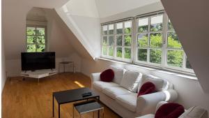a living room with a white couch and windows at Villa Am Park in Bad Homburg vor der Höhe