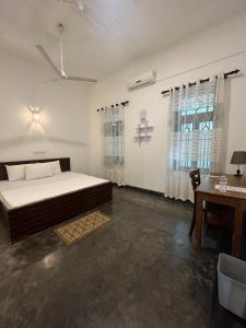 a bedroom with a large bed and a desk at Ali Bungalow - Galle in Galle
