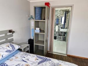 a small bedroom with a bed and a shower at Elmscote Cottages - Cabin 2 in Krugersdorp