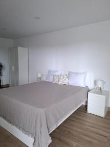 a white bedroom with a large bed and two lamps at Casa Machado in Cangas de Morrazo