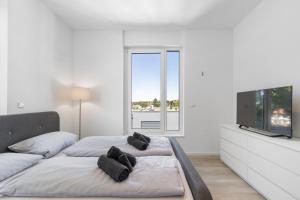 una camera bianca con un grande letto e una TV a schermo piatto di LivingBoxx Karlsruhe - Messe I neuwertige Apartments mit Küche a Rheinstetten