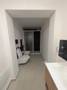 a white bathroom with a toilet and two sinks at Appartamento a due passi dal mare in Martinsicuro