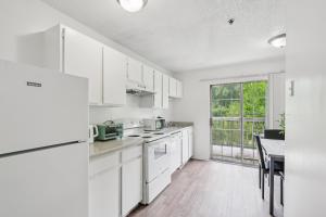 a white kitchen with white cabinets and a table at Kenridge Apartments 1635 I Comfy 2 Bed 2 Bath in Decatur