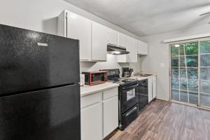 Una cocina con gabinetes blancos y un refrigerador negro. en Kenridge Apartments 2605 I Comfy 2 Bed 2 Bath, en Decatur