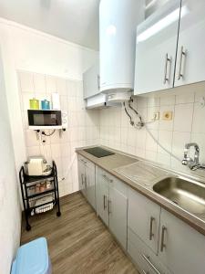 Una cocina con gabinetes blancos y un fregadero. en Casa da Praia na Torre Castelo, en Armação de Pêra