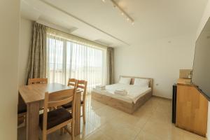 a bedroom with a bed and a table and a dining room at апартаменти Пасажио in Sandanski