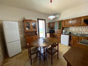 a kitchen with a table and a white refrigerator at Villa Iris- indipendente sul mare in Sorso