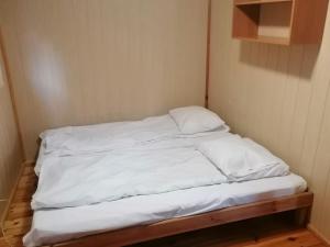 a small bed with white sheets and pillows on it at Amber Coast - Domek nr 4 in Jantar