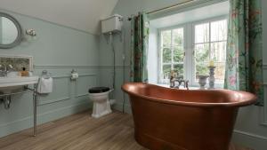 a bathroom with a tub and a toilet and a window at Gardener's Cottage, Twizell Estate in Belford