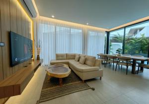 un salon avec un canapé, une télévision et une table dans l'établissement Bangtao Luxury Pool Villa - PrymaVerde, à Laguna Phuket
