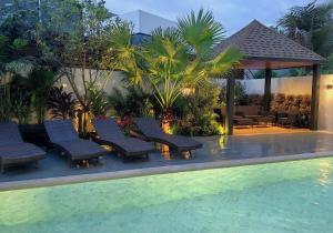 un groupe de chaises assises à côté d'une piscine dans l'établissement Bangtao Luxury Pool Villa - PrymaVerde, à Laguna Phuket