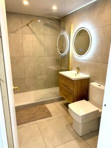 a bathroom with a toilet and a sink and a shower at Sienna Cottage in Benllech