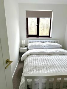 a white bedroom with a bed and a window at Sienna Cottage in Benllech