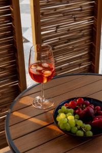 a glass of wine and a plate of fruit on a table at Lumora Suites in Kavos +73 photos