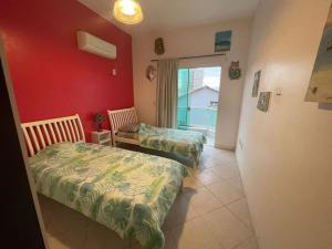 a room with two beds in a room with red walls at A Pérola do Gravatá in Navegantes