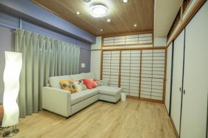 a living room with a couch and a lamp at Nagoya Apartment Oosu in Minami-sotoborichō