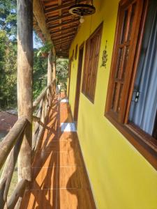 een veranda van een geel huis met een houten hek bij Refúgio do Paraty Mirim in Paraty
