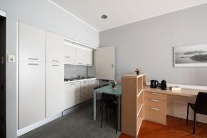 a kitchen with white cabinets and a green table at Appartamento in Centro 10' Stazione in Turin