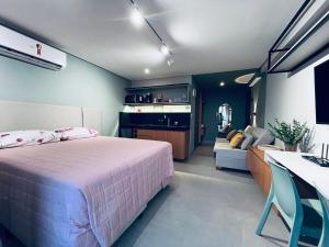 a bedroom with a bed and a couch and a kitchen at Flat Lindo e Espaçoso com Varanda e Vista Mar in João Pessoa