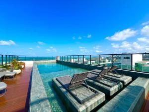 a swimming pool with two chairs on top of a building at Flat Lindo e Espaçoso com Varanda e Vista Mar in João Pessoa