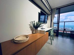 a living room with a tv and a table with a desk at Flat Lindo e Espaçoso com Varanda e Vista Mar in João Pessoa +22 photos