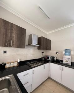 a kitchen with white cabinets and a stove top oven at Modern Airport Studio apartment 5 mins to JKIA &SGR,Fast Wi-Fi,Ideal for layovers and longstays in Nairobi +9 photos