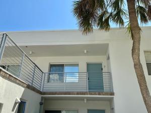a white house with a balcony and a palm tree at 7th Heaven condo in Longboat Key +18 photos