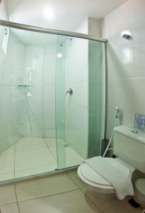 y baño con ducha de cristal y aseo. en Hotel Corais de Tambau, en João Pessoa