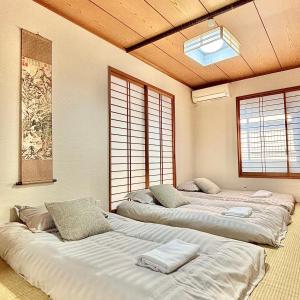 a room with three beds in it with windows at CEREZO House in Osaka