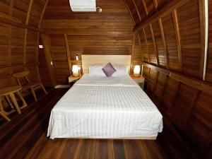 a bedroom with a white bed in a wooden room at De Ravin Bungalows Canggu in Dalung