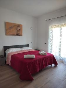 a bedroom with a red bed with two towels on it at B&B La Foglietta in Paganica