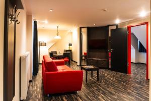 a living room with a red couch and a table at Altora Eisenbahn Themenhotel in Wernigerode