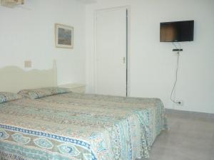 Un dormitorio con una cama y un televisor en la pared. en Apartamentos Jorbar, en El Arenal