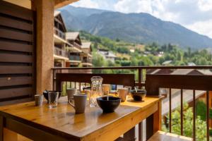 a wooden table on a balcony with a view of a mountain at Mas de Blais appartement Chaleureux à 5 minutes des pistes in Briançon