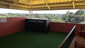 a room with a balcony with a view of trees at Le Chateau - Scarlet Ibis Apartment in Point Fortin