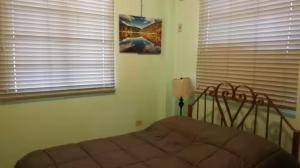 a bedroom with a bed in front of a window at Le Chateau - Scarlet Ibis Apartment in Point Fortin