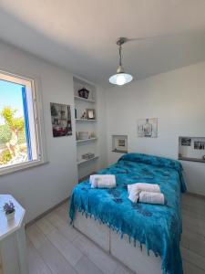 a bedroom with a bed with blue sheets and a window at Marilù Casa Vacanza in San Vito lo Capo