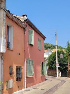 an orange building with green shutters on a street at Sanceflo in Mandelieu-La Napoule