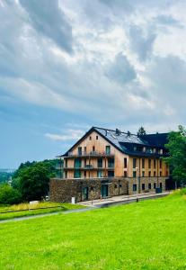 a large building with a green field in front of it at Stylový apartmán Ski&Bike, Janské Lázně in Janske Lazne