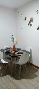 a dining room with a black table and white chairs at Departamento céntrico y comodo in Santa Cruz de la Sierra