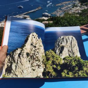 a person holding a book with a picture of rocks at Delizioso appartamento a Capri in Capri