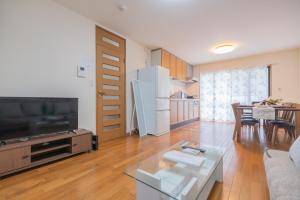 a living room with a large television and a kitchen at CEREZO House in Osaka