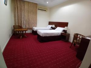 a hotel room with two beds and a red carpet at فندق جوهرة ميسر in Quai
